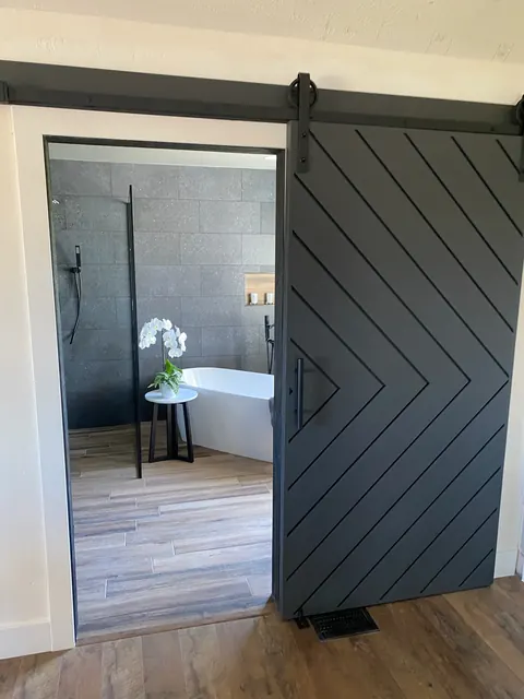 Bathroom with a sliding barn door, freestanding tub and large-format tile shower