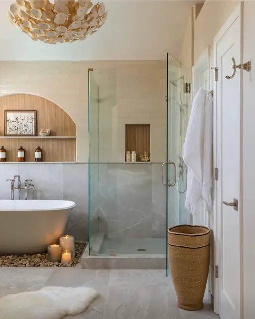 Primary bathroom with a soaking tub, frameless glass shower and river rock accent bed