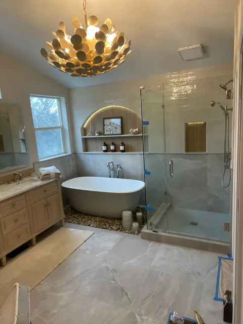 Primary bathroom with a freestanding soaking tub, frameless glass shower and gold petal chandelier