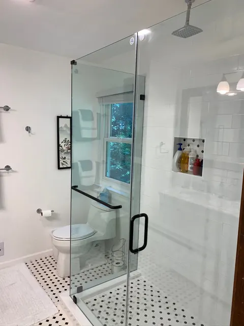 Remodeled bathroom with a frameless glass shower and black and white hex tile floor