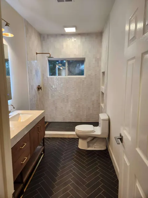 Bathroom remodel with dark herringbone tile flooring and a tiled walk-in shower