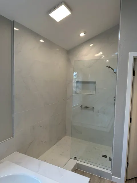 Walk-in shower finished in large-format marble-look porcelain tile