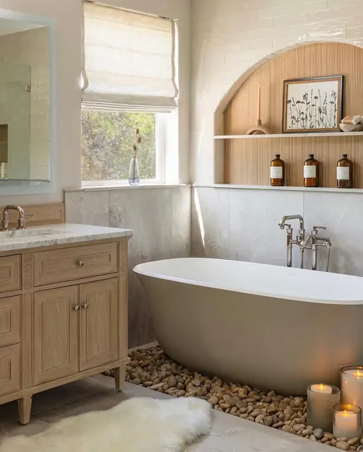 Primary bathroom with a white oak vanity, marble counter and freestanding soaking tub