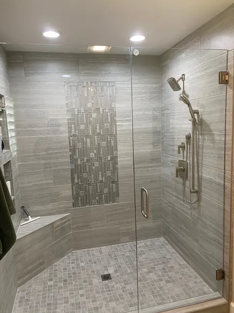 Walk-in shower with large-format tile and a vertical glass mosaic accent band