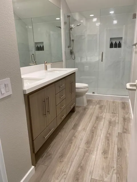 Bathroom remodel with a wood vanity, quartz counter and frameless glass shower