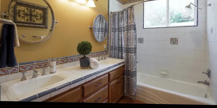 Bathroom before remodel: yellow walls, a tiled vanity counter and a tub and shower combination