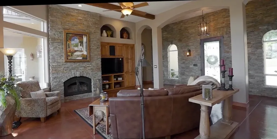 Living room before remodel: stone fireplace with wood built-ins, ceiling fan and dark stained floors