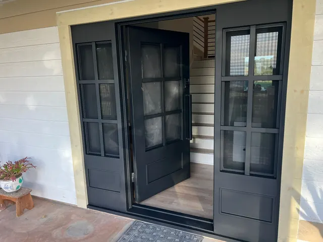 Black double entry doors with divided-light glass and matching sidelights