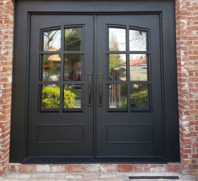 Custom black steel entry doors with divided-light glass set into a brick facade