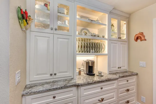 Built-in kitchen hutch with glass display cabinets, a plate rack and granite counter