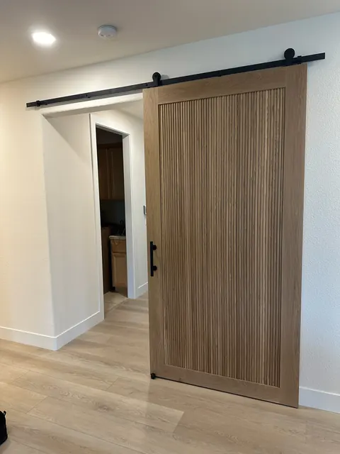 Custom fluted white oak barn door on a black steel track