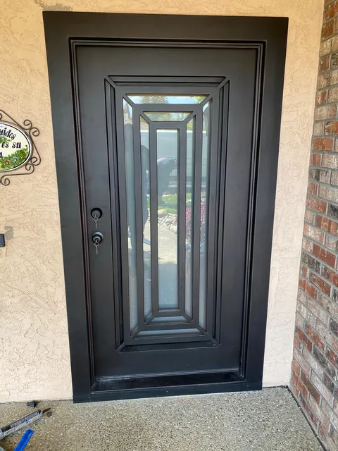Custom iron front entry door with a beveled glass panel and brick surround