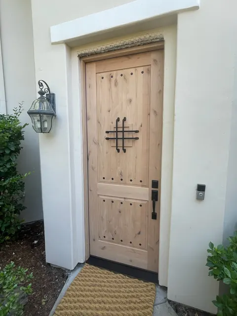 Rustic knotty alder front door with decorative iron hardware and clavos
