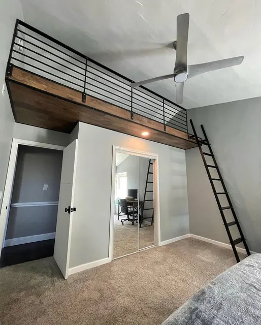 Custom loft mezzanine with a black steel railing, reclaimed wood facing and a library ladder