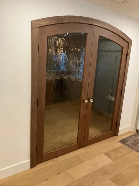 Custom arched walnut double doors with textured seeded glass panels