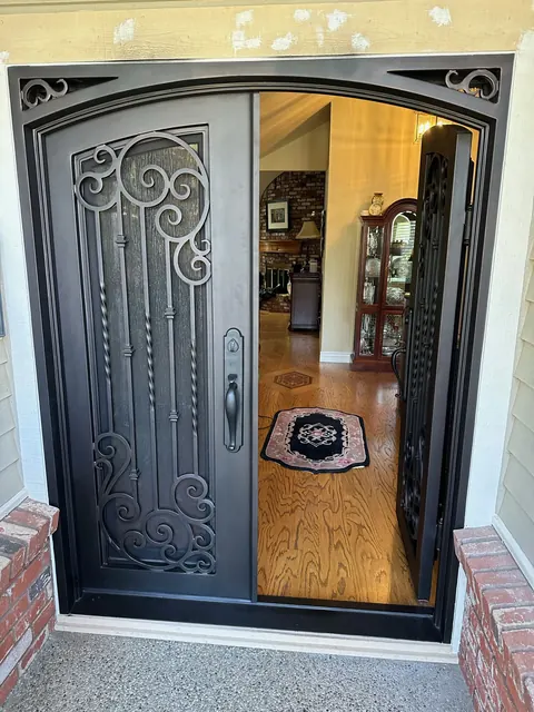Ornate wrought iron and glass front entry door opening into a tiled foyer