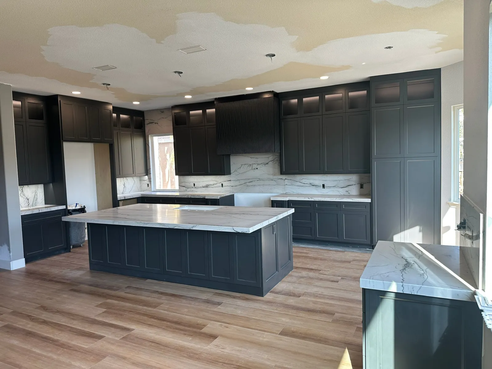 Kitchen remodel with charcoal cabinetry, a marble island and full-height stone backsplash