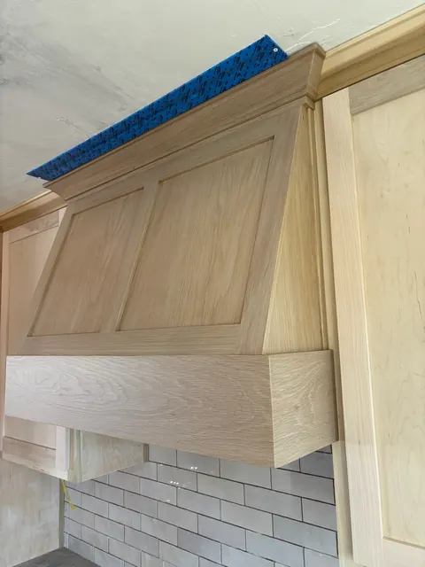 Custom white oak range hood being built on site, showing the joinery before finish