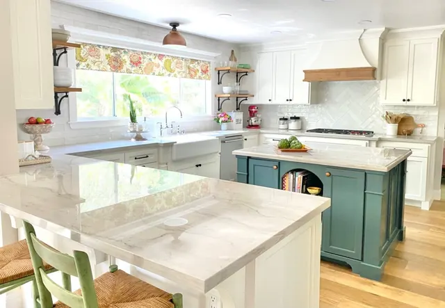 White kitchen remodel with a deep green island, stone counters and open shelving