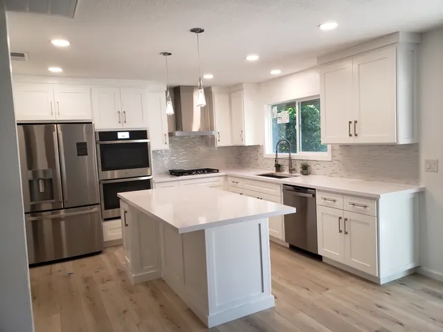 Remodeled white shaker kitchen with a center island, quartz counters and stainless appliances