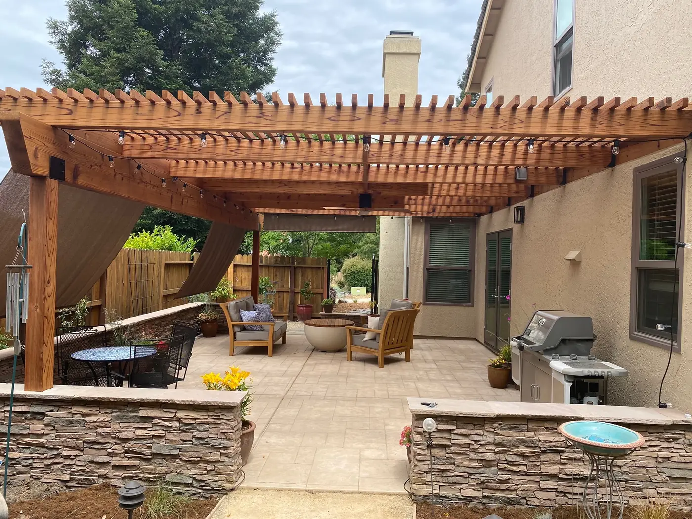 Outdoor living space with a cedar pergola, stacked stone bar and built-in barbecue