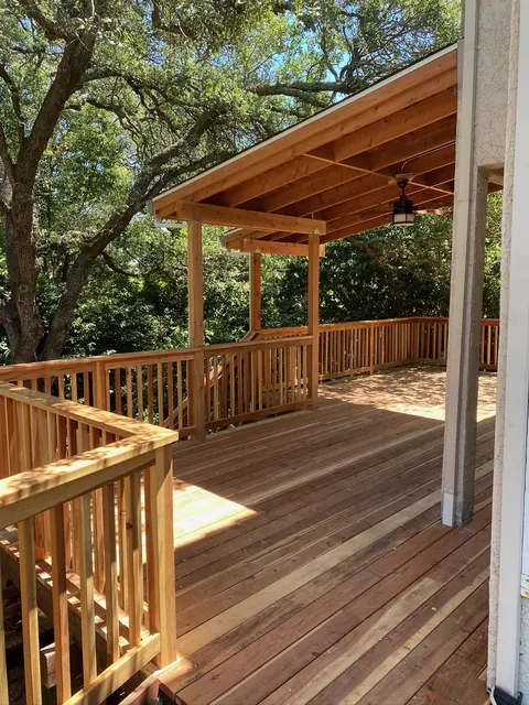 Covered deck pavilion with wood railing and a tongue-and-groove ceiling shaded by oaks