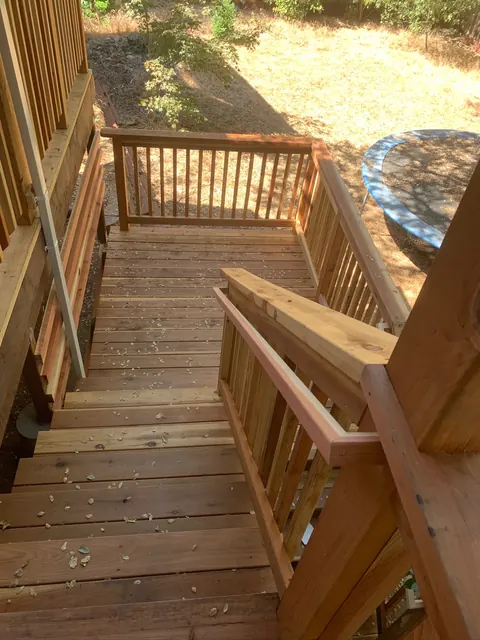 Wood deck stairs and railing leading down to a backyard seating area