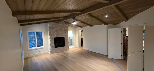 Great room remodel with exposed wood beams and a stone fireplace