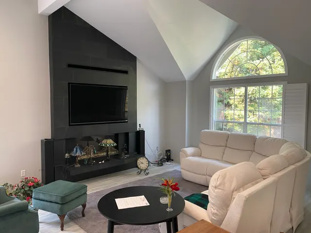 Great room with a floor-to-ceiling tile fireplace wall, mounted television and vaulted ceiling