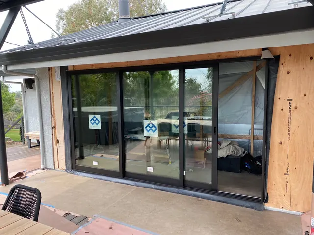 Home addition under construction with a standing seam metal roof and multi-slide glass door